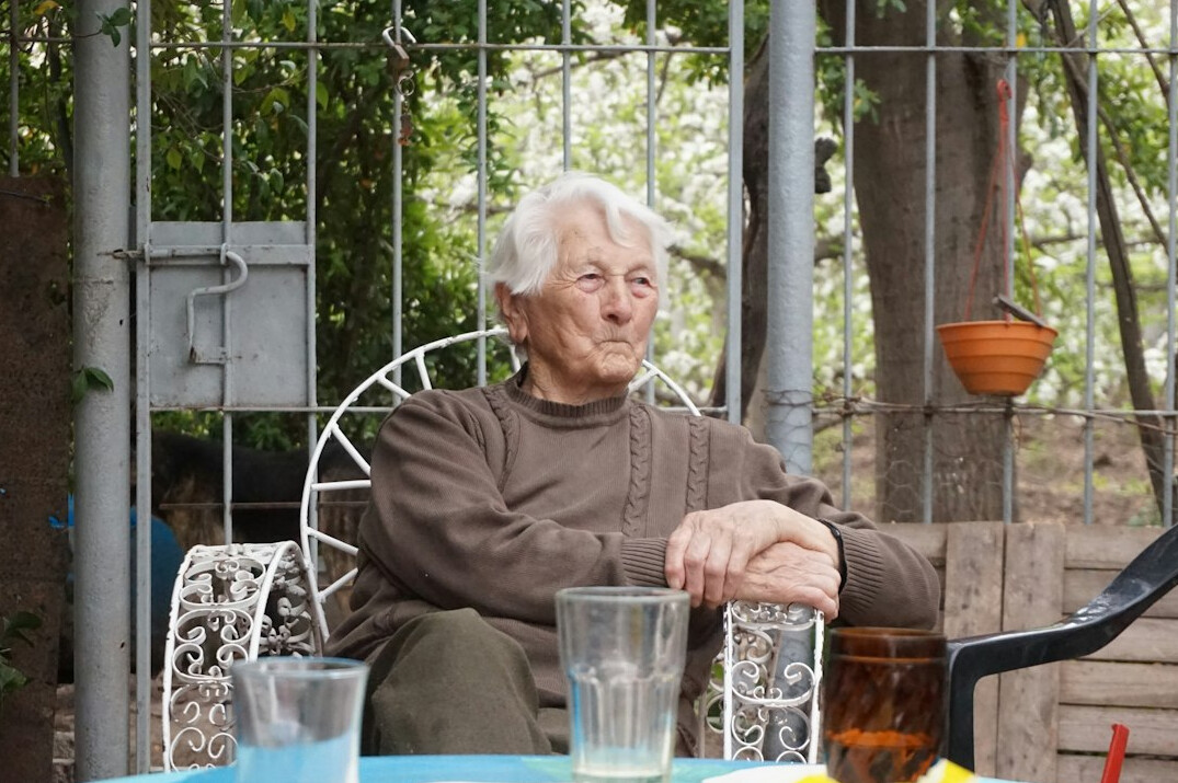Smiling senior woman with short grey hair holding a tablet at a bright table